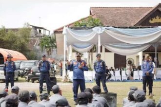 Tak Hanya Jaga Lingkungan, Satlinmas Bandar Lampung Dibekali Keterampilan Hadapi Bencana Pembekalan tersebut diberikan melalui rangkaian pelatihan peningkatan kapasitas yang digelar di Lapangan Kepayang, Gedung Herman HN, Kota Bandar Lampung, Jumat (25/9/2026). Dalam kegiatan itu, anggota Satlinmas mendapat pelatihan pemadam kebakaran dari Dinas Pemadam Kebakaran dan Penyelamatan. Mereka diberikan pengetahuan mengenai langkah awal menghadapi kebakaran, termasuk tindakan keselamatan dan penanganan awal sebelum mendapat penanganan lebih lanjut dari petugas. Selain kebakaran, anggota Satlinmas juga mendapat materi penanggulangan bencana dari Badan Penanggulangan Bencana Daerah (BPBD). Materi yang diberikan mencakup kesiapsiagaan, mitigasi serta langkah-langkah yang perlu dilakukan ketika terjadi bencana atau keadaan darurat di lingkungan masyarakat. Pembekalan ini diarahkan agar anggota Satlinmas memiliki kemampuan dasar untuk merespons kondisi darurat di lingkungan tempat mereka bertugas. Posisi Satlinmas yang berada dekat dengan masyarakat dinilai membuat kemampuan tersebut penting dimiliki. Pelatihan juga mencakup materi kepramukaan yang diberikan untuk mendukung pembentukan karakter, kedisiplinan, kerja sama dan kepemimpinan anggota. Rangkaian kegiatan tersebut menjadi bagian dari upaya meningkatkan kapasitas Satlinmas Bhakti Karya Kota Bandar Lampung agar lebih siap menghadapi berbagai kondisi yang membutuhkan respons cepat. Dengan pembekalan dari unsur pemadam kebakaran, BPBD dan kepramukaan, anggota Satlinmas diharapkan tidak hanya mampu menjalankan tugas perlindungan masyarakat, tetapi juga memiliki kesiapan dasar ketika menghadapi kebakaran maupun bencana di lingkungan sekitar.