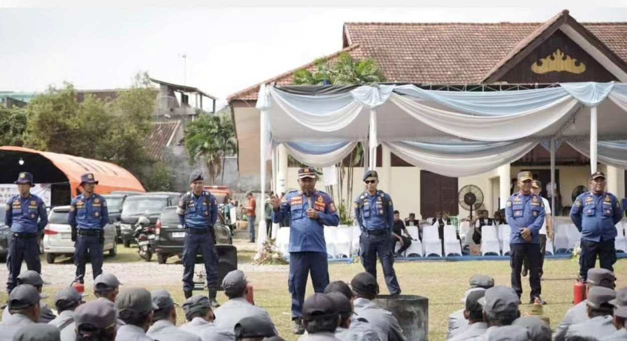 Tak Hanya Jaga Lingkungan, Satlinmas Bandar Lampung Dibekali Keterampilan Hadapi Bencana Pembekalan tersebut diberikan melalui rangkaian pelatihan peningkatan kapasitas yang digelar di Lapangan Kepayang, Gedung Herman HN, Kota Bandar Lampung, Jumat (25/9/2026). Dalam kegiatan itu, anggota Satlinmas mendapat pelatihan pemadam kebakaran dari Dinas Pemadam Kebakaran dan Penyelamatan. Mereka diberikan pengetahuan mengenai langkah awal menghadapi kebakaran, termasuk tindakan keselamatan dan penanganan awal sebelum mendapat penanganan lebih lanjut dari petugas. Selain kebakaran, anggota Satlinmas juga mendapat materi penanggulangan bencana dari Badan Penanggulangan Bencana Daerah (BPBD). Materi yang diberikan mencakup kesiapsiagaan, mitigasi serta langkah-langkah yang perlu dilakukan ketika terjadi bencana atau keadaan darurat di lingkungan masyarakat. Pembekalan ini diarahkan agar anggota Satlinmas memiliki kemampuan dasar untuk merespons kondisi darurat di lingkungan tempat mereka bertugas. Posisi Satlinmas yang berada dekat dengan masyarakat dinilai membuat kemampuan tersebut penting dimiliki. Pelatihan juga mencakup materi kepramukaan yang diberikan untuk mendukung pembentukan karakter, kedisiplinan, kerja sama dan kepemimpinan anggota. Rangkaian kegiatan tersebut menjadi bagian dari upaya meningkatkan kapasitas Satlinmas Bhakti Karya Kota Bandar Lampung agar lebih siap menghadapi berbagai kondisi yang membutuhkan respons cepat. Dengan pembekalan dari unsur pemadam kebakaran, BPBD dan kepramukaan, anggota Satlinmas diharapkan tidak hanya mampu menjalankan tugas perlindungan masyarakat, tetapi juga memiliki kesiapan dasar ketika menghadapi kebakaran maupun bencana di lingkungan sekitar.